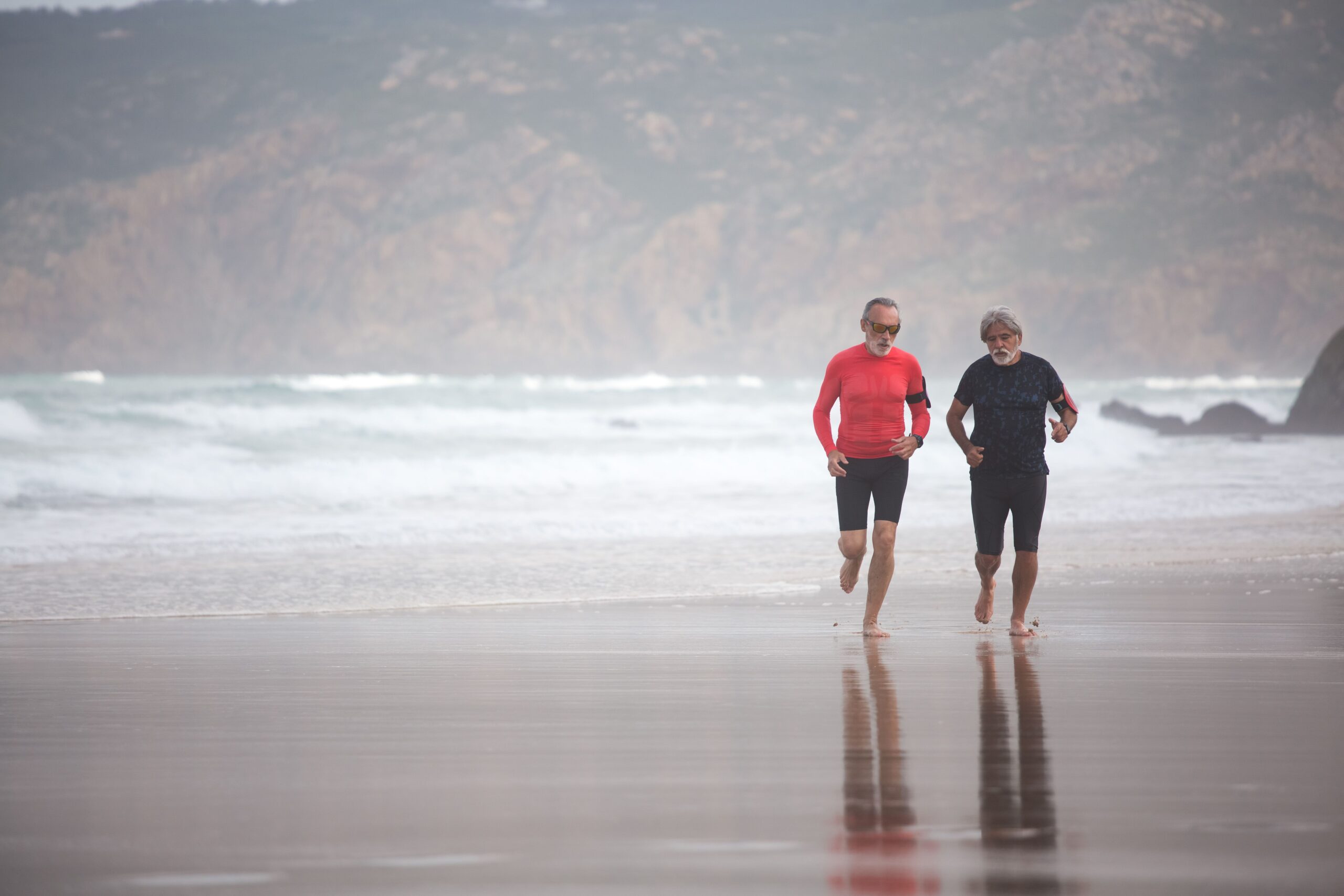 Elderly men jogging on a scenic beach in Portugal, embodying fitness and healthy living.